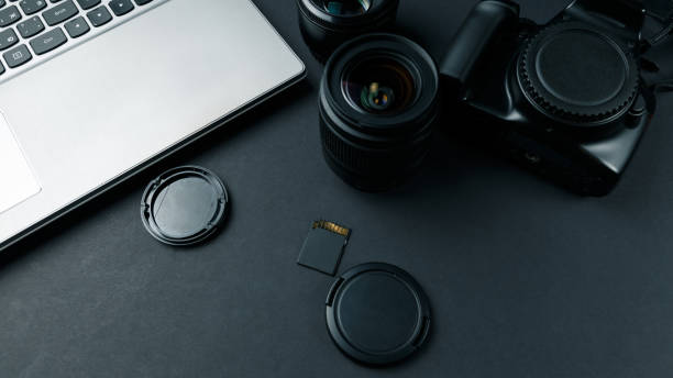 istock Work space on black table of photographer. Minimal workspace with Laptop, camera and lens copy space on dark background. Modern and elegant. 1044968364