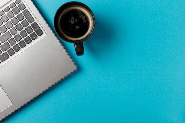 istock Minimal workspace with Laptop and coffee Cup copy space on blue background. Top view. Flat lay style. 1044969060