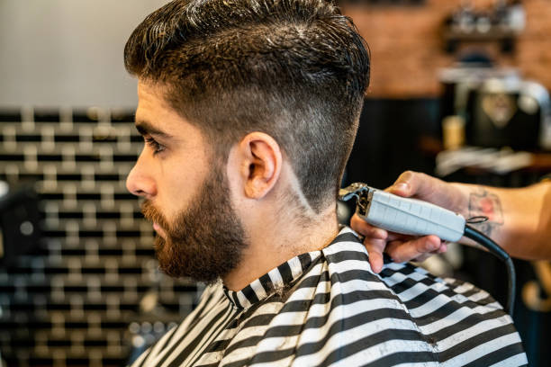 istock Close up of handsome customer getting a haircut and unrecognizable barber using an electric shaver 1044971482