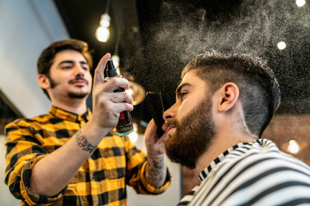 istock Young hair dresser using hair spray on customer 1044971504