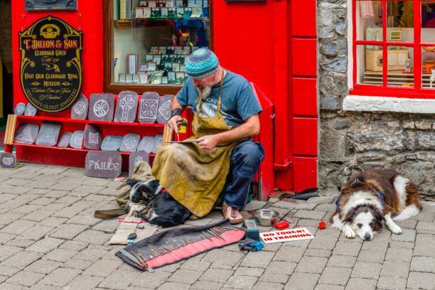 Galway, Ireland - August 07, 2018: A sculptor is working on a slate outdoors in one of the main pedestrian streets in Galway.