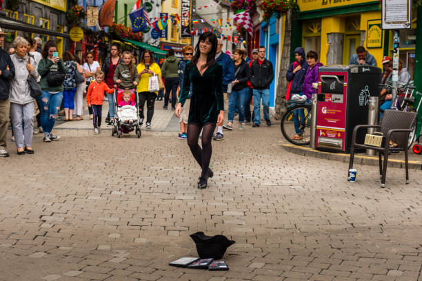 Galway, Ireland - August 07, 2018: People walking along one of the main pedestrian streets in Galway. It is full of shops, pubs and restaurants.  A girl is tap-dancing.