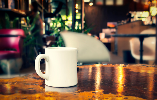 Coffee cup or ceramic mug on wooden table on the café coffee shop blurred background with copy space for your text and logo.