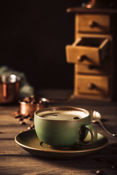 Green cup of coffee with coffee grinder