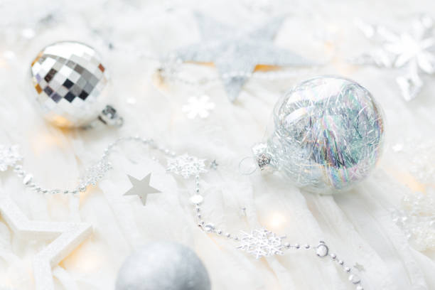 istock Christmas and New Year holiday background with decorations and light bulbs. Silver and white shining balls, snowflakes and star confetti. 1044980384