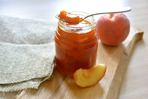 항아리에 숟가락 복숭아 살구 잼 - peach jam 뉴스 사진 이미지