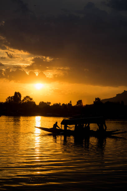 Silhouette of a boat riding over the Dal Lake during sunset