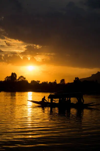 Silhouette of a boat riding over the Dal Lake during sunset