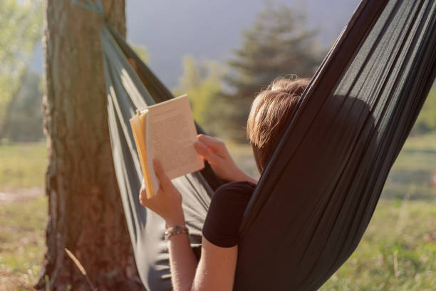 istock young woman reading a book on a hammock during sunset 1044997812