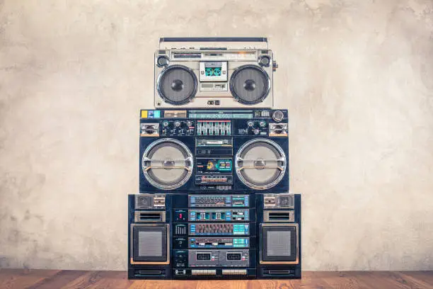 Retro design ghetto blaster stereo radio cassette tape recorders boombox tower from circa 80s front concrete wall background. Vintage instagram old style filtered photo