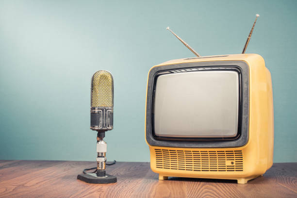 istock Retro old outdated yellow TV receiver from circa 70s and studio microphone on wooden table front mint green wall background. Vintage style filtered photo 1045003734