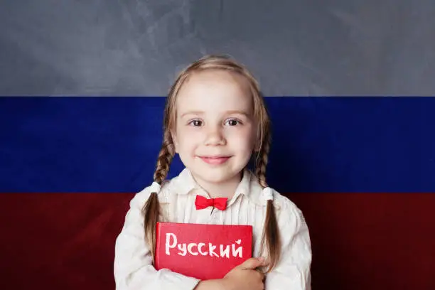 Photo of Learn russian language. Child girl student with book against the russian flag background