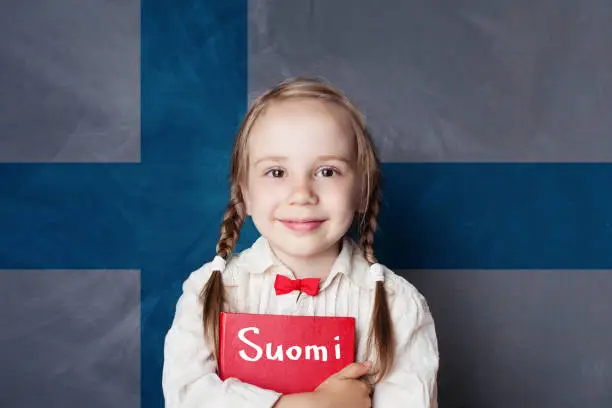 Photo of Learning finnish language. Smart child girl on the Finnish flag background