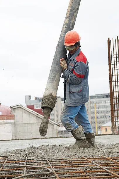 builder worker aiming pump tube during concrete pouring process