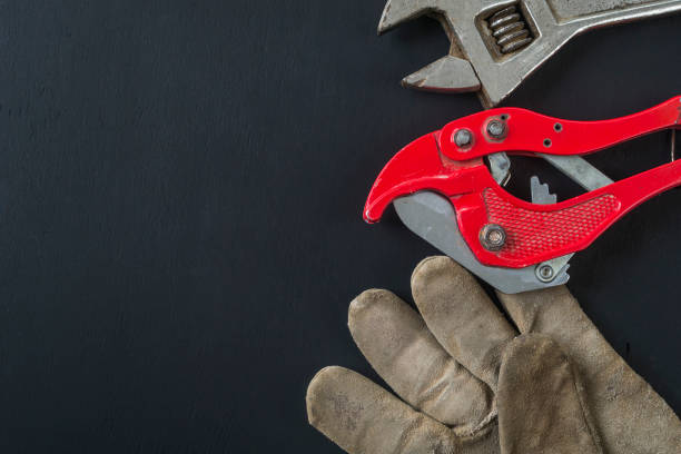 istock Wrench, old gloves and scissors for cutting polypropylene pipes on a black background. 1045012394