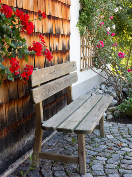 istock Wooden bench on cobblestone pavement against wooden wall 1045018292
