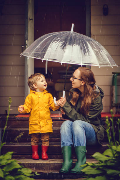 Mother and son in raincoats walking in rain