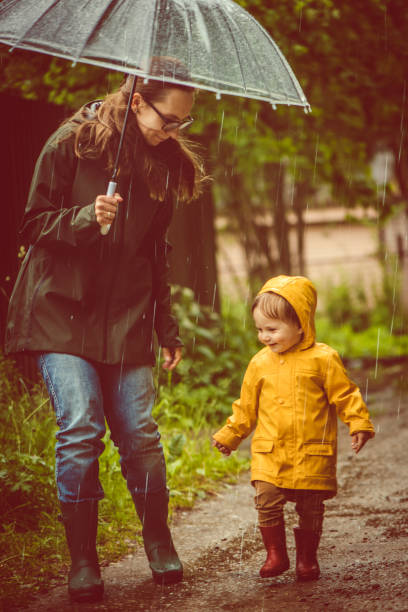 istock Mother and son in raincoats walking in rain 1045021082