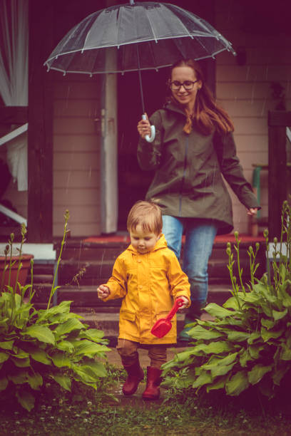 istock Mother and son in raincoats walking in rain 1045021090