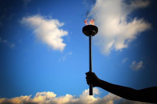 istock Close up man holding burning flaming torch over cloudy sky 1045026878