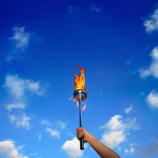 istock Close up man holding burning flaming torch over cloudy sky 1045029244