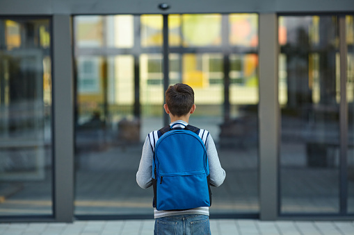Colegial está parado delante de la puerta de la escuela photo