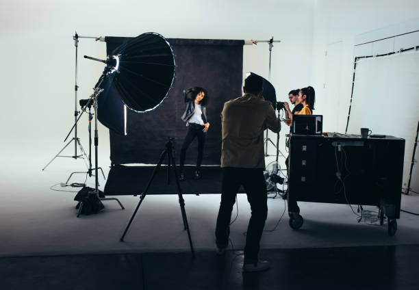 Photographer with his crew during a photo shoot in studio. Photographer shooting photos of a female model with studio flash lights on. Photographer with his team during a photo shoot. crew photos stock pictures, royalty-free photos & images