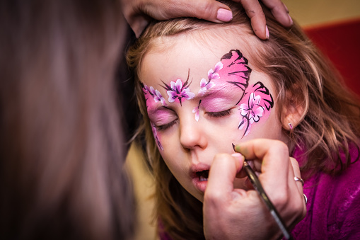 Little girl having her face painted during party