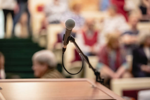 istock Microphone on abstract blurred of speech in seminar room or speaking conference hall light, Event Background 1045043694