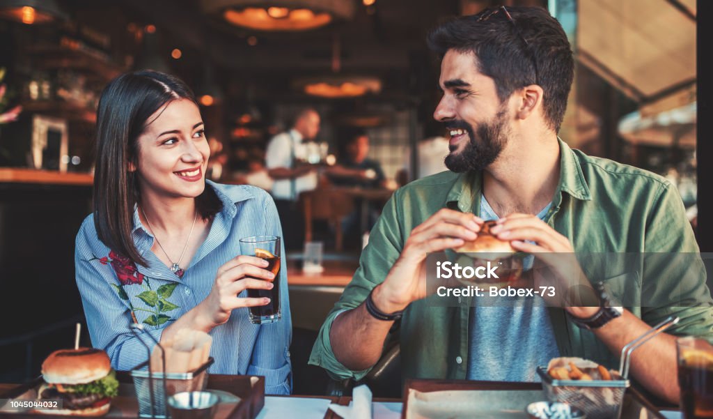 Beau jeune couple assis dans un café, en prenant son petit déjeuner. Amour, rencontres, nourriture, concept lifestyle - Photo de Manger libre de droits