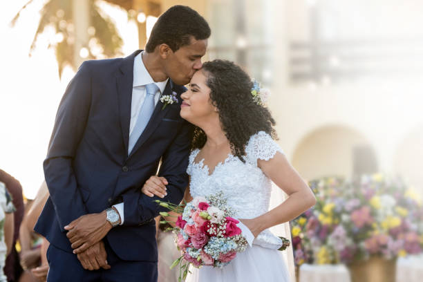 bräutigam küsst seine braut auf der stirn - wedding black american culture bride stock-fotos und bilder