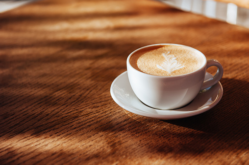 coffee cup latte art in cafe on wooden table