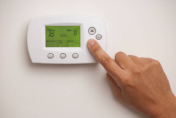 hombre mano en el termostato digital establecido en 78° - termostato fotografías e imágenes de stock