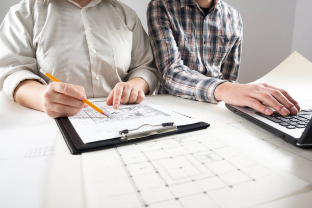 istock Architects working on blueprint, real estate project. Architect workplace - architectural project, blueprints, ruler, calculator, laptop and divider compass. Construction concept. Engineering tools. 1045079714