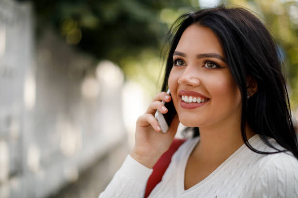istock Smiling young woman using mobile phone outdoors 1045082344