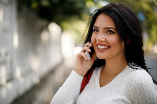 istock Smiling young woman using mobile phone outdoors 1045082390
