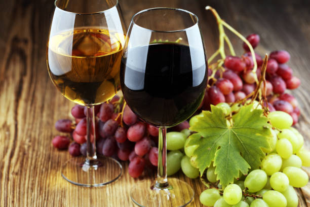 istock White wine and red wine in a glass with fall grapes on rustic background. 1045096280