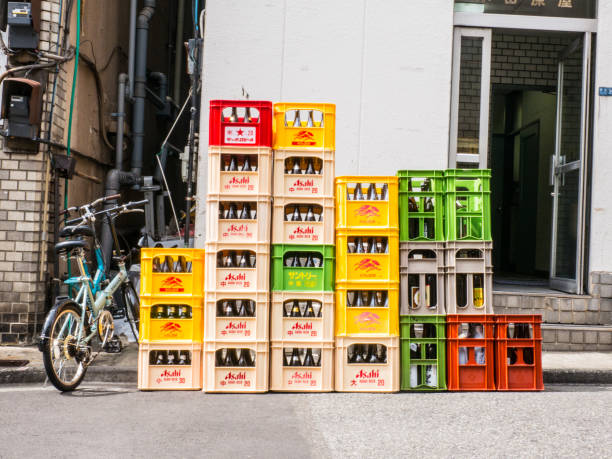 A close up of stacks of plastic red, white, and yellow crates containing Asahi beer and soft drink bottles in Japan. stock photo