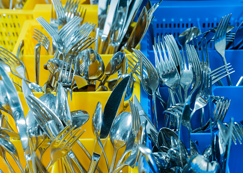 silverware and cutlery in colorful palstic ocntainer in an industrial restaurant kitchen clean and fresh out of the dishwasher