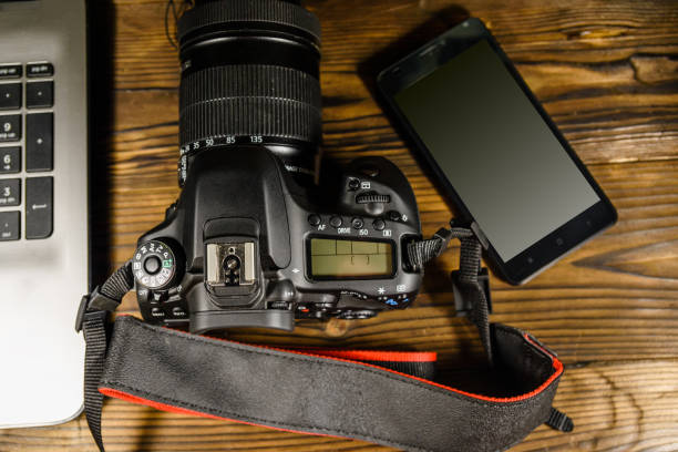 istock Modern DSLR camera, smartphone and laptop on wooden table. Top view 1045161954