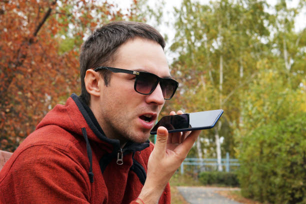 recording on dictaphone. leisure, technology, communication and people concept - hipster man using voice command recorder or calling on smartphone at autumn park. dictate the thoughts in entry. - conference phone imagens e fotografias de stock