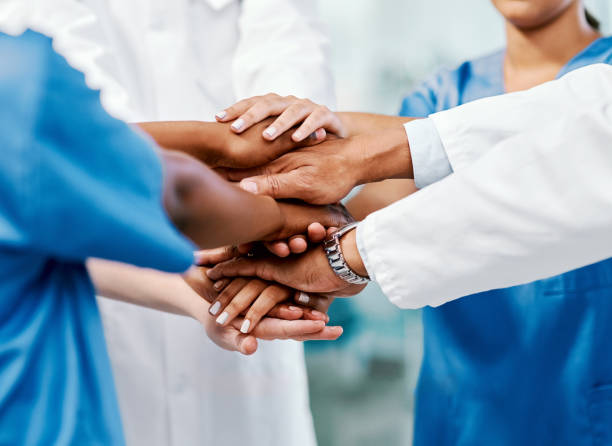 We share the same passion Closeup shot of a group of medical practitioners joining their hands together in a huddle caregivers day stock pictures, royalty-free photos & images