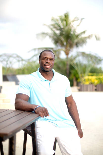 istock Handsome black man is smiling He is sitting closed to table with palm background 1045200970