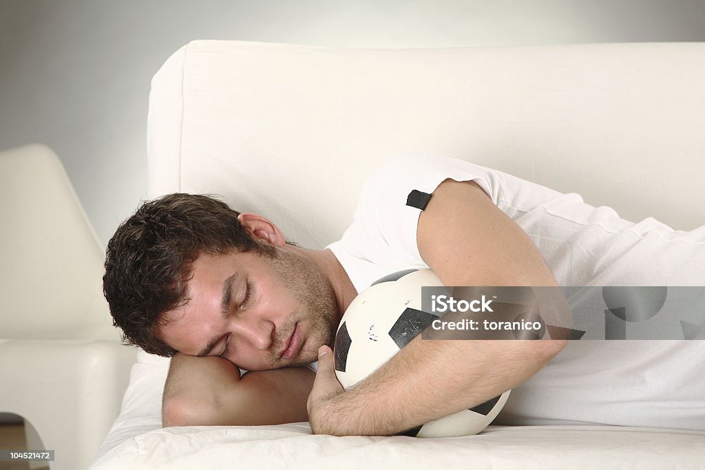 young man sleeping with ball on sofa  Adult Stock Photo