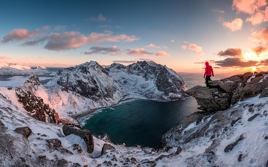 Man mountaineer standing on rock of peak mountain at sunset. Ryten Mountain, Norway