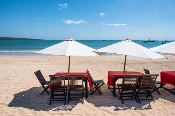 istock Red wooden dining table with white umbrella on the beach 1045220874