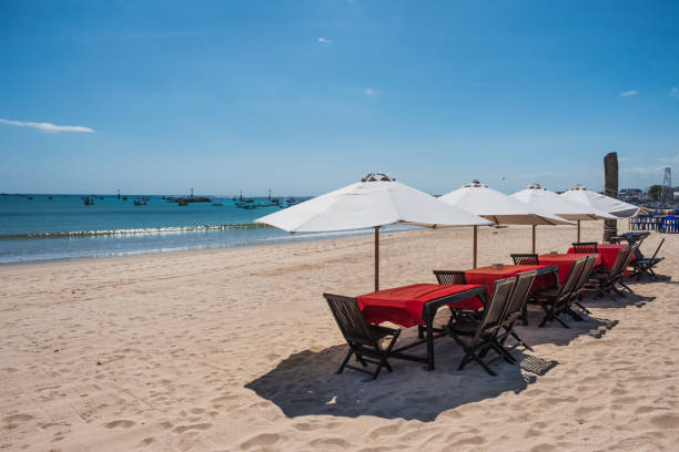 istock Red wooden dining table with white umbrella on the beach 1045220878