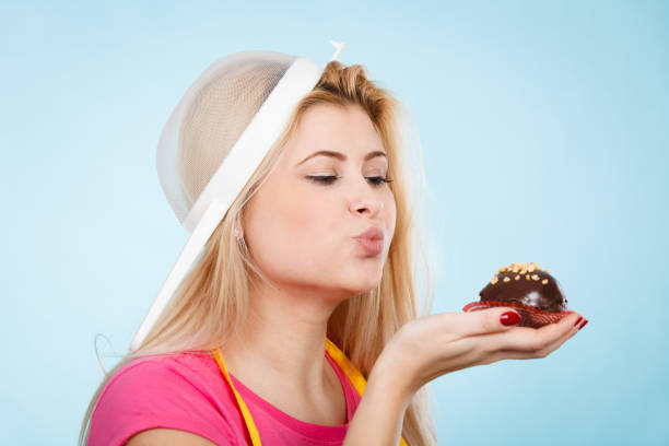 Young happy woman tasting a cake from her arm while having it all over her face.