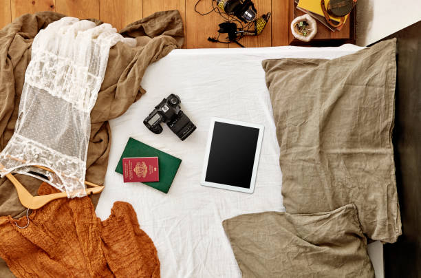 istock Digital tablet, passport and photo camera on messy bed - clipping path on screen 1045245292