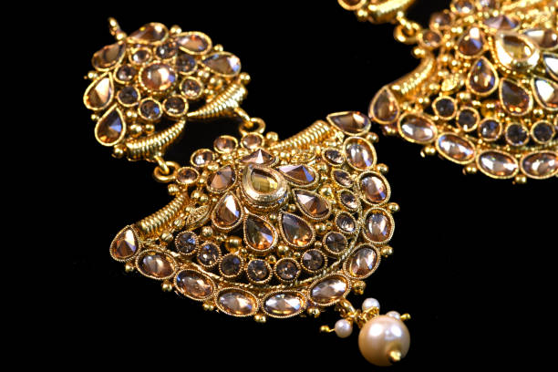 istock Fancy designer golden earring set closeup macro image on black background 1045248936